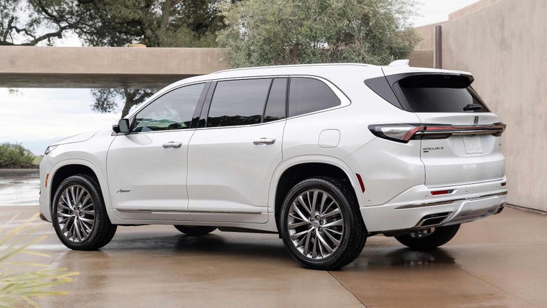 Three-Quarter Rear View of a 2025 White Buick Enclave in Front of a Bridge