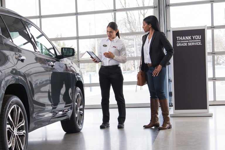 A Service Advisor speaking with a customer next to a vehicle