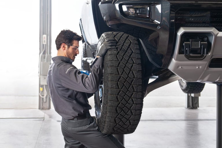 A Service Technician replacing a wheel on a vehicle
