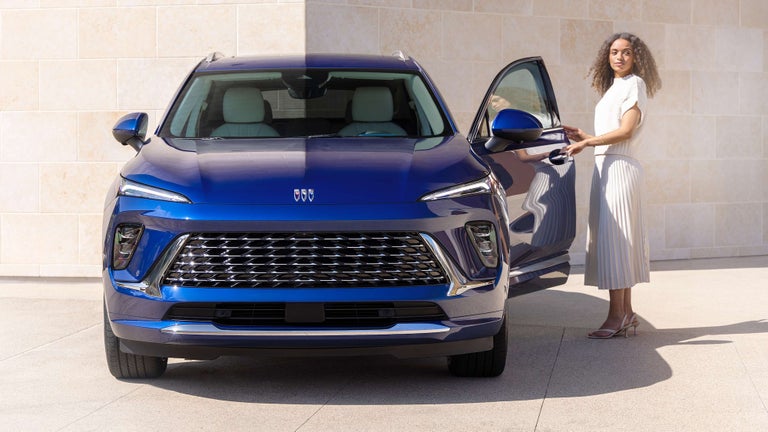 A Person Opening the Door of a Front Facing Blue Buick Envision Avenir
